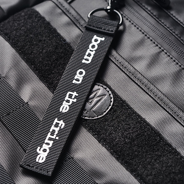 Moral NIGHTHAWKS MILITARY 軍事風托特包中碼細節特寫,突出品牌織帶標語與魔鬼氈設計。質感細膩,展現軍事風格與個性化裝飾空間。