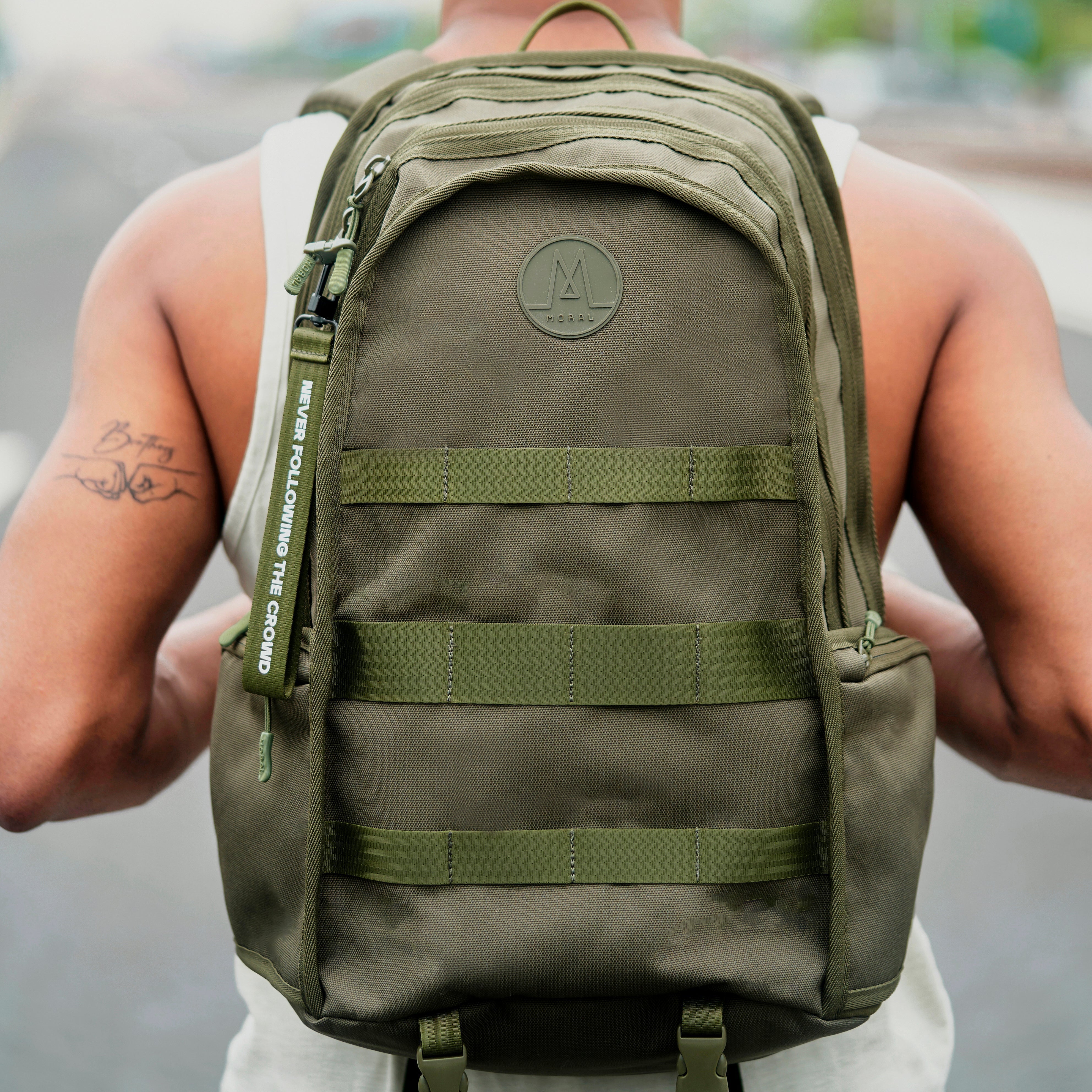 MORAL Napier Poser 運動背包大碼軍綠色,正面有多條實用織帶與品牌標誌。包款設計堅固,適合戶外及日常多元用途。