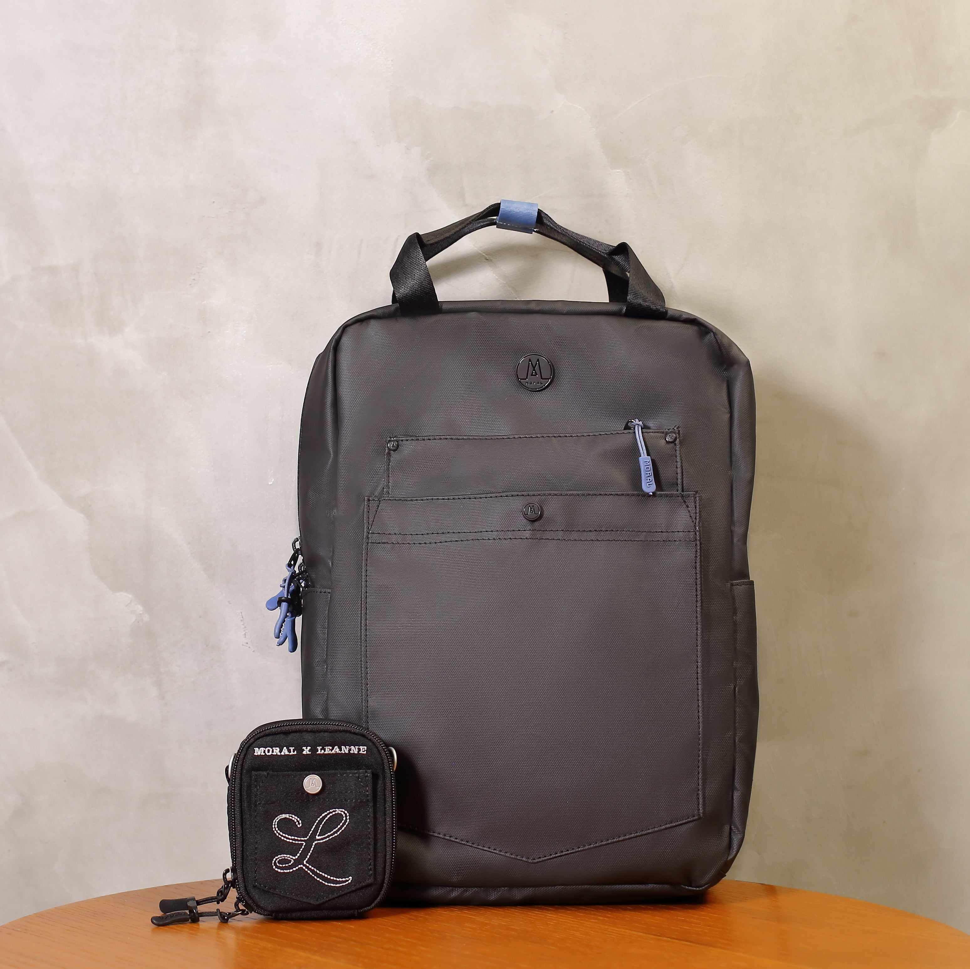 Moral x Leanne.LY Budd Gizza 背包頂部設有堅固手提把與品牌皮標細節。展現實用提把設計與品牌經典元素。